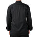 A man wearing a Mercer Culinary black long sleeve chef jacket with a white background.