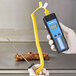 A person using a Cooper-Atkins DuraNeedle probe with a yellow spiral cable to check food on a grill.