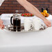 A man holding a Vollrath stainless steel serving tray with coffee cups and a coffee maker.