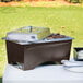 A Sterno WindGuard Copper Vein chafer frame on a table with food in metal containers.