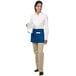 A woman wearing a white shirt and a royal blue Chef Revival waist apron holding a glass of ice.