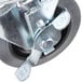 A close up of a black metal swivel plate caster with a metal bolt.