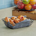 A Tablecraft black rectangular wire basket filled with pastries on a counter.