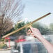 A hand using a Unger brass squeegee to clean a window.