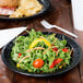 A Dart foam plate with a vegetable salad, sandwich, and drink on a table.