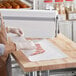 A person wearing gloves wrapping a piece of meat in Choice white freezer paper.