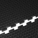 A close-up of a black Cactus Mat with holes in it.