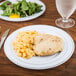 A Fineline white plastic plate with silver bands filled with chicken and macaroni on a table.