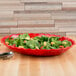 A red Cambro deli crock filled with salad on a table.