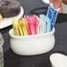 A person putting a sugar packet in a white bowl.