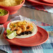 A Tuxton Concentrix Cinnebar plate with shrimp tacos, black beans, and cheese.