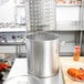 A chef using a Vollrath Wear-Ever Boiler / Fryer Set to pour water into a large pot.