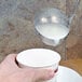 A hand using a Vollrath stainless steel ladle to pour white liquid into a cup.