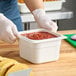 A person holding a Cambro white plastic food container filled with food.