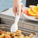 A person using Cambro white plastic tongs to serve food.