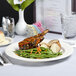 A Tuxton Monterey ivory china plate with food on a table.
