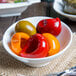 A bowl of red and yellow food in an Arcoroc Ludico bowl on a white table.