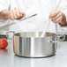 A chef using a Vollrath Miramar casserole pan to cook.