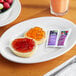 A plate with a piece of bread and a bowl of grape and mixed fruit jelly on a table.