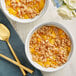 Two bowls of diced peaches with spoons on a table.