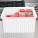 A white Metro divider tote box holding jars of red and white spices.