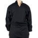A woman wearing a black Mercer Culinary long sleeve chef jacket with cloth knot buttons.