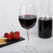 A Chef & Sommelier tall wine glass filled with red wine next to crackers and strawberries.