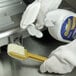 A person in white gloves using Meat Slicer Safety Cleaning Kit to spray and clean a metal surface.