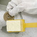 A gloved hand uses a sponge and brush to clean a circular wheel.