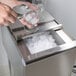 A person pouring ice from an Eagle Group underbar ice chest into a glass.