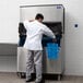 A man in a white shirt standing in front of a large Manitowoc air cooled ice machine.