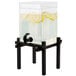 A Cal-Mil black plastic beverage dispenser with lemons on a stand and ice chamber.