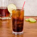 A clear plastic highball glass of iced tea with a straw and a lime slice on top.