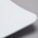 A close-up of a white GET Milano square melamine plate with a curved edge.