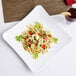 A white square melamine plate with a serving of pasta on it next to a glass of wine.