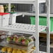 A white Cambro Camshelving® Premium vented shelf unit with fruit and vegetables on it.