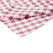 A folded red and white checkered Intedge vinyl table cover.