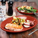 A Scarlet Fiesta china platter with food on a table with a fork and knife.
