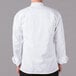 A man wearing a white Mercer Culinary long sleeve chef jacket with cloth knot buttons.