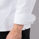 The sleeve of a white Mercer Culinary long sleeve chef jacket with cloth knot buttons.