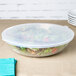 A Fineline clear plastic bowl of salad on a table.