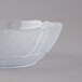 A Carlisle clear polycarbonate bowl with a leaf design on it.
