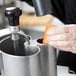 A person in a plastic glove using a Robot Coupe CL50 Ultra food processor to prepare a carrot.