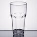 A close-up of a Carlisle clear plastic tumbler with a rim on a table.