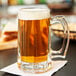 A Libbey beer mug full of beer on a table.