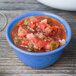 A bowl of peacock blue melamine with salsa on a wood table.