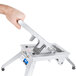 A hand holding a silver Vollrath Pusher Head Assembly for a Vollrath Redco Onion King on a white table.