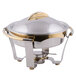 A Vollrath Panacea large round chafer with a gold lid and stainless steel base on a table outdoors.