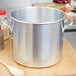 A Vollrath Wear-Ever aluminum stock pot on a wooden surface.