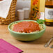 A Tuxton pasta bowl filled with spaghetti and sauce on a table with a bottle of wine.